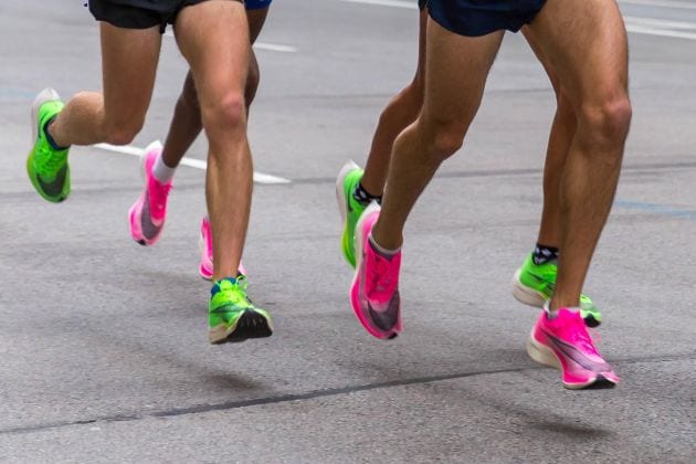 Legs of marathon runners wearing Nike ZoomX Vaporfly Next% running shoes in the pink and green versions. Photo by Marco Verch via Flickr