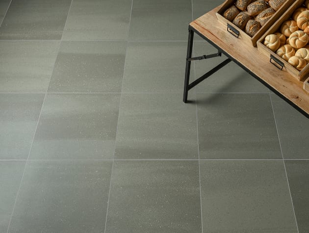 grey tiled floor with corner of table with bread rolls